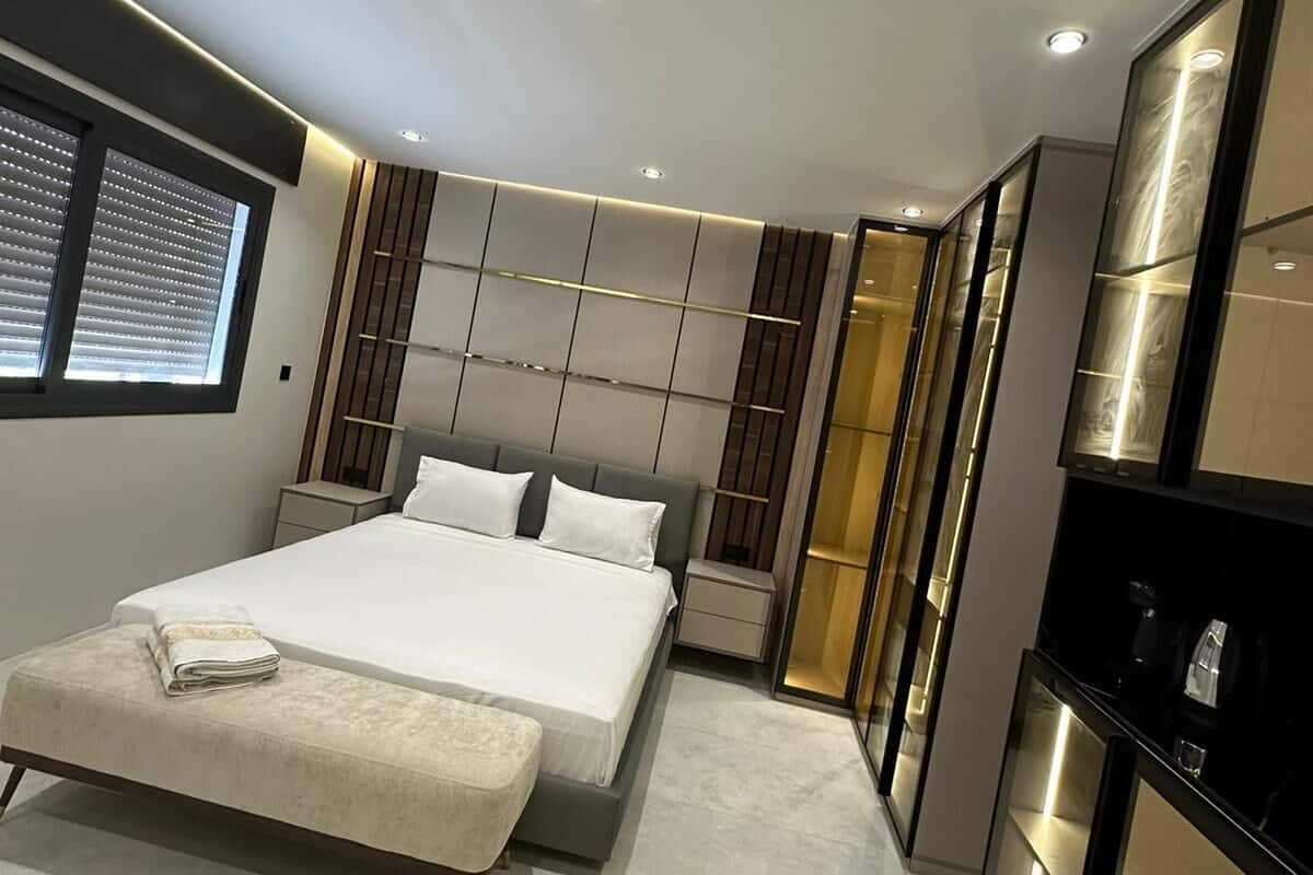 A modern bedroom with a large bed, built-in shelving, and a walk-in closet.