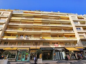 A multi-story hotel with balconies, storefronts below, and a clear blue sky above. - N&J - MELODIE DU SUD - Central - Near Beach (Niza)