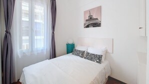 A bedroom with a bed, curtains, a nightstand, and a wall-mounted picture of a bridge. - N&J - SAVOY PROMENADE - Central - Near Beach (Niza)
