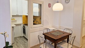 A dining area with a wooden table and metal chairs, a hanging light fixture, and a clock on the wall. - N&J - SAVOY PROMENADE - Central - Near Beach (Niza)