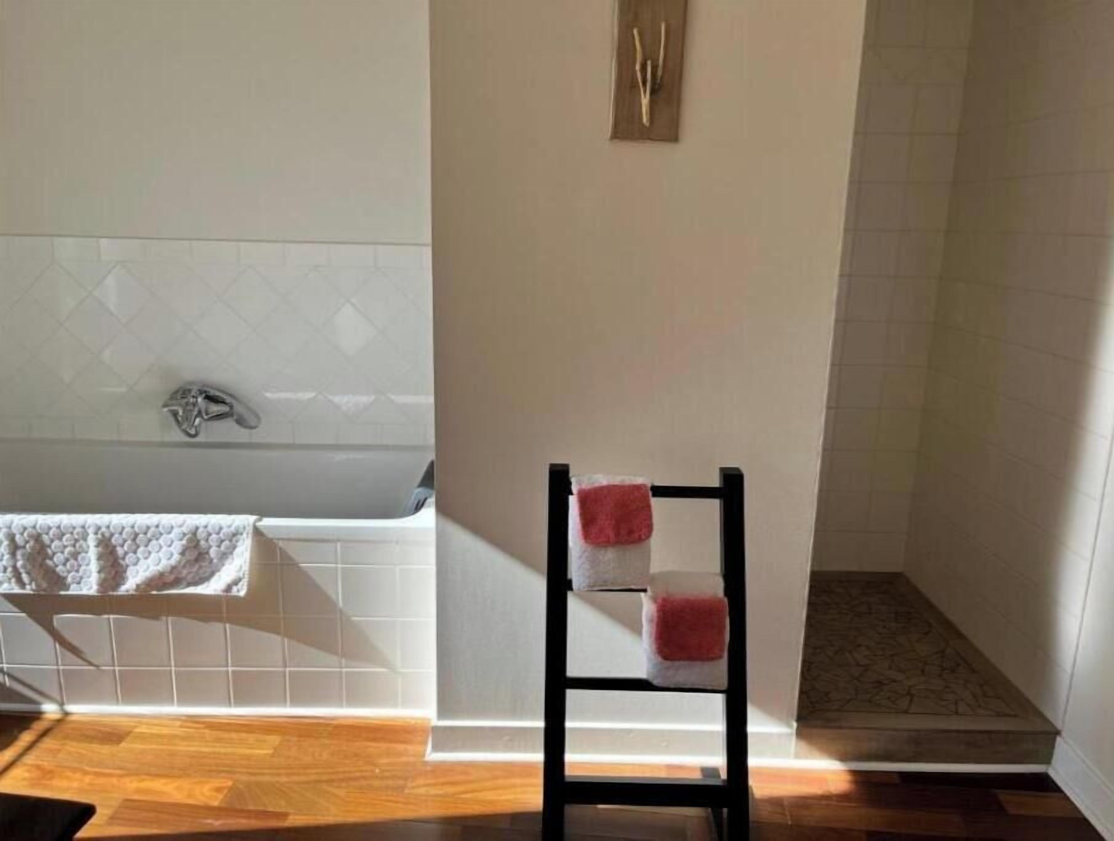 A bathroom with a bathtub, a shower, and a wooden floor.