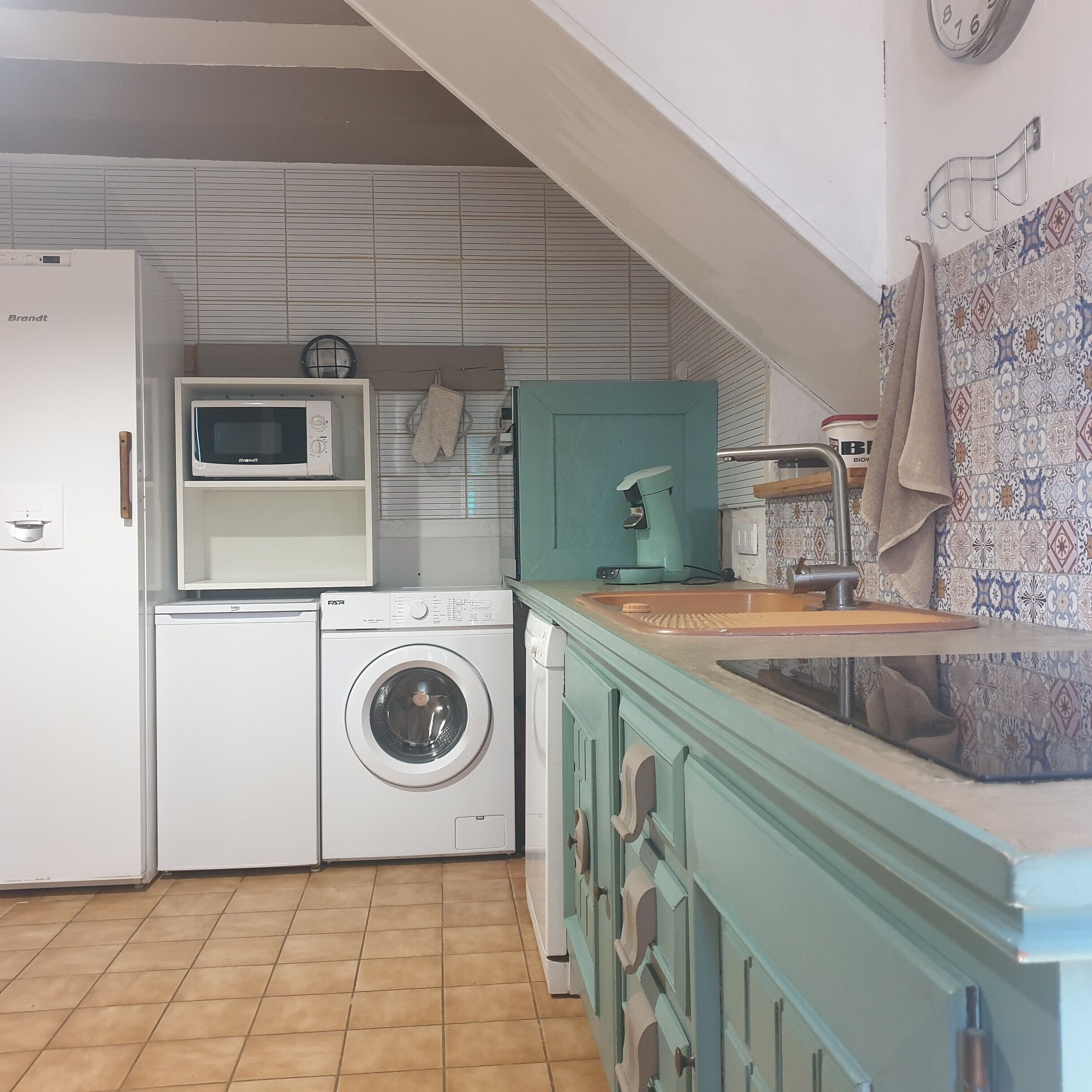 Una cucina funzionale con lavatrice, forno a microonde e lavello.