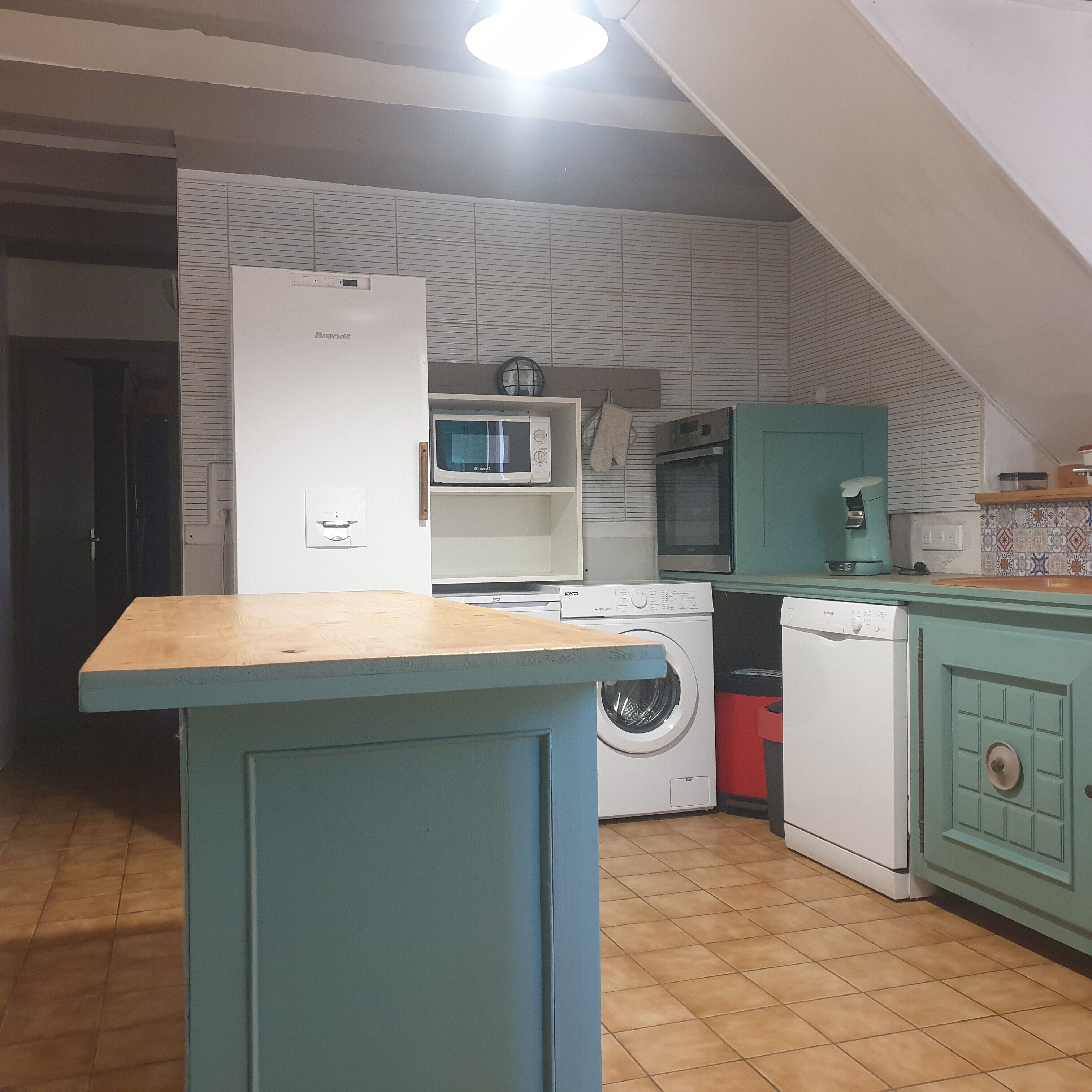 A kitchen with a washing machine, a microwave, and a sink.