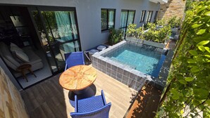 Un área de piscina moderna al aire libre, con borde de azulejos, sillas de mimbre azul y una mesa redonda.