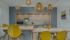 Una cocina moderna con una isla central, sillas amarillas e iluminación colgante.