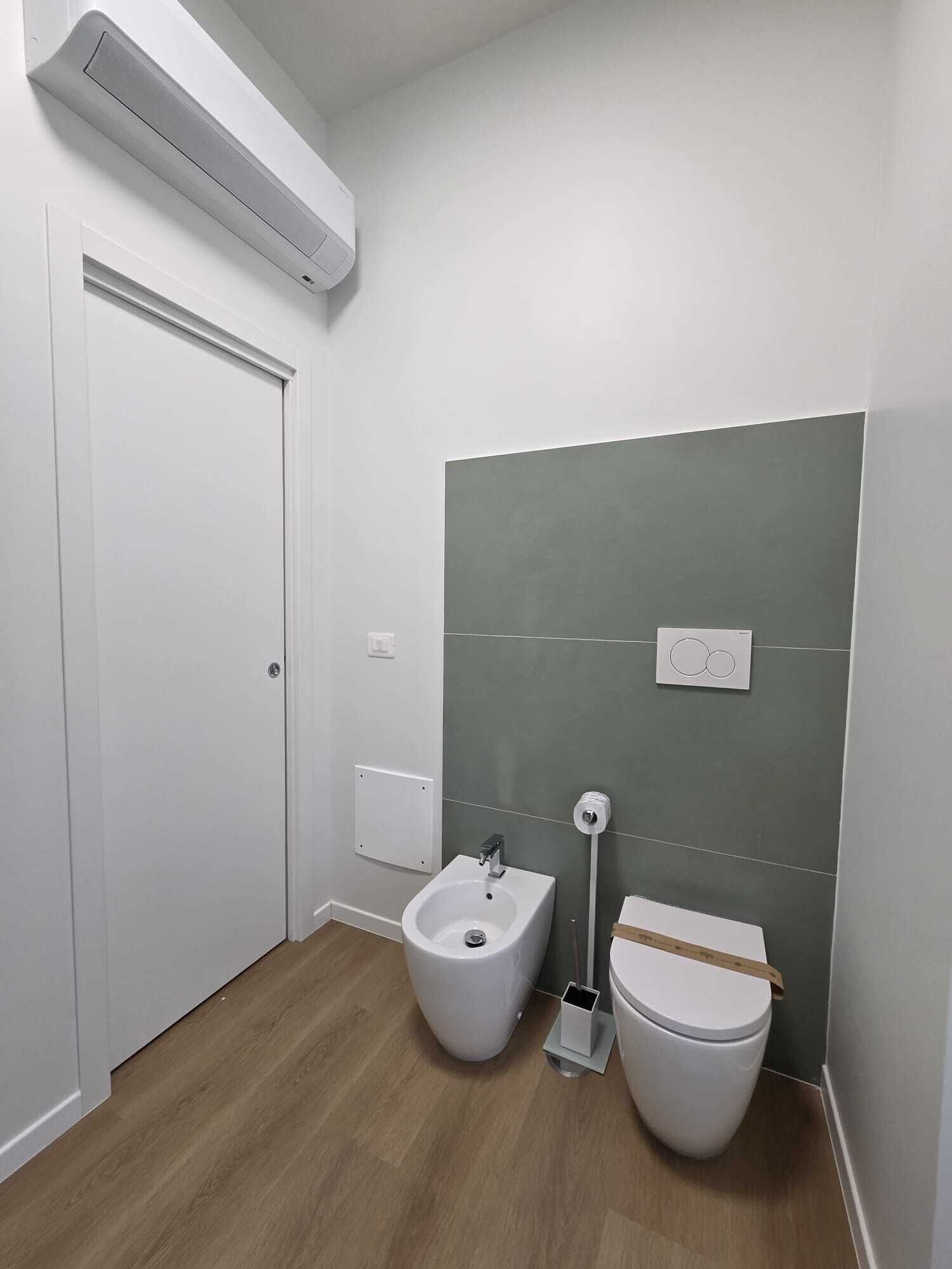 Une petite salle de bain avec un bidet, des toilettes et une porte blanche.