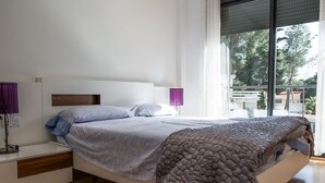 A modern bedroom with a bed, bedside tables, and a large window. - Dream Villa in Cap Salou - Pool & Beach Paradise (Salou)