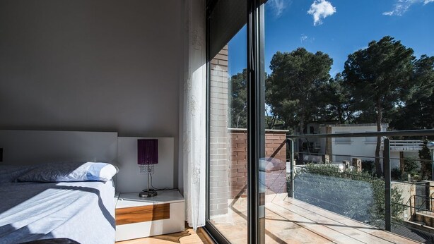 A bedroom with a large window, a bed, a bedside table, and a view of the outside. - Dream Villa in Cap Salou - Pool & Beach Paradise (Salou)