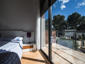 A bedroom with a large window, a bed, a bedside table, and a view of the outside. - Dream Villa in Cap Salou - Pool & Beach Paradise (Salou)