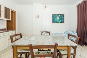 Un coin repas avec une table en granit, des chaises en bois, un vase et un tableau accroché au mur.