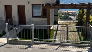 Un bâtiment avec un toit recouvert de tuiles, une entrée fermée par un portail et une vue sur des montagnes en arrière-plan.