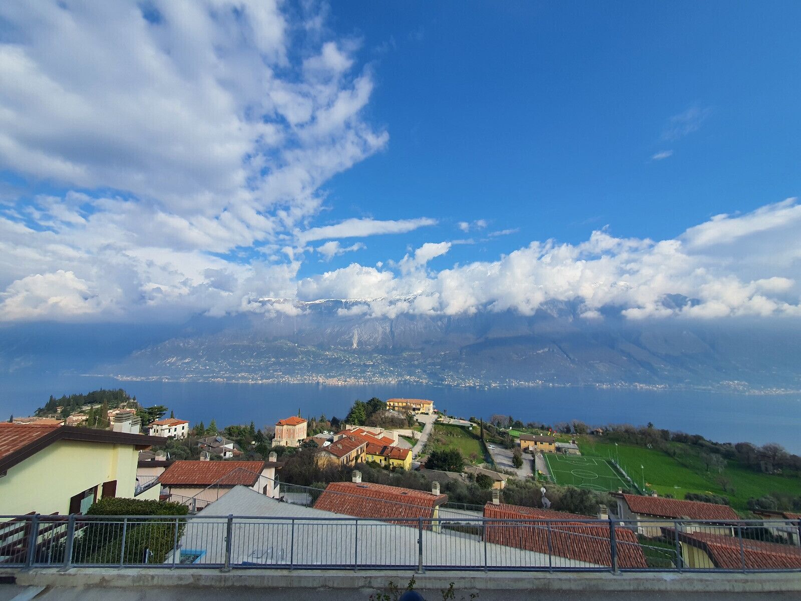 A coastal town with buildings on a hillside, a clear sky, and a mountain in the background.