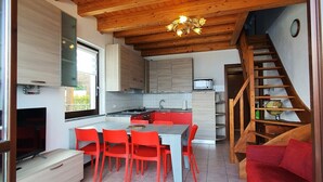Une cuisine moderne avec des poutres en bois, un coin repas avec des chaises rouges et un canapé rouge.
