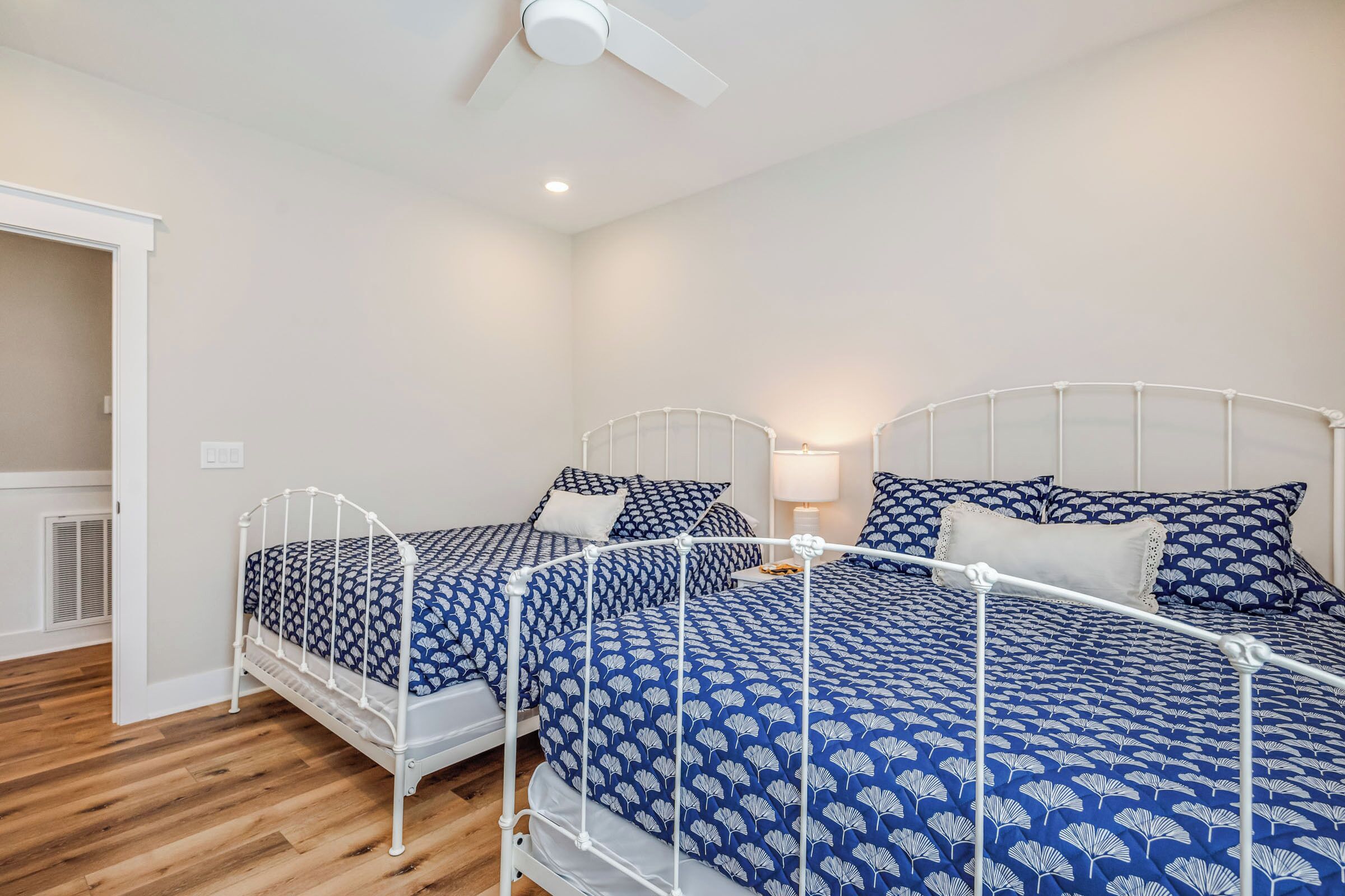 A bedroom with two beds, a ceiling fan, and a bedside lamp.