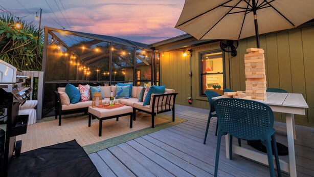 An outdoor patio with a covered seating area, a table with a jenga tower, and string lights. - Family Resort Near Beaches, with Heated Pool, Hot Tub, Mini Golf & Games (Bradenton)