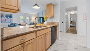 A modern kitchen with granite countertops, wooden cabinets, and a dishwasher. - Family Resort Near Beaches, with Heated Pool, Hot Tub, Mini Golf & Games (Bradenton)