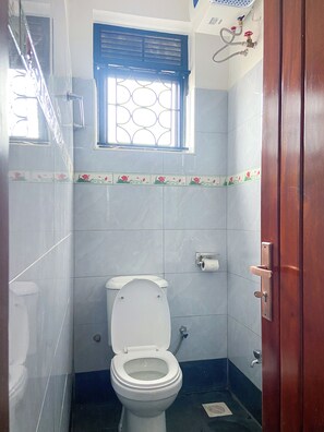 Une petite salle de bain comprenant des toilettes, une fenêtre et un espace douche.