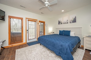 A bedroom with a bed, a ceiling fan, a nightstand, a dresser, and a painting on the wall.