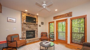 A cozy living room with a stone fireplace, two leather armchairs, a coffee table, and a sign reading "Deep Creek Lake".