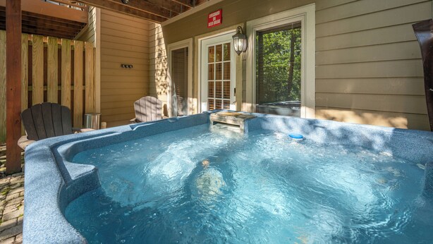 A hot tub in a covered outdoor area with wooden beams and a wooden fence.