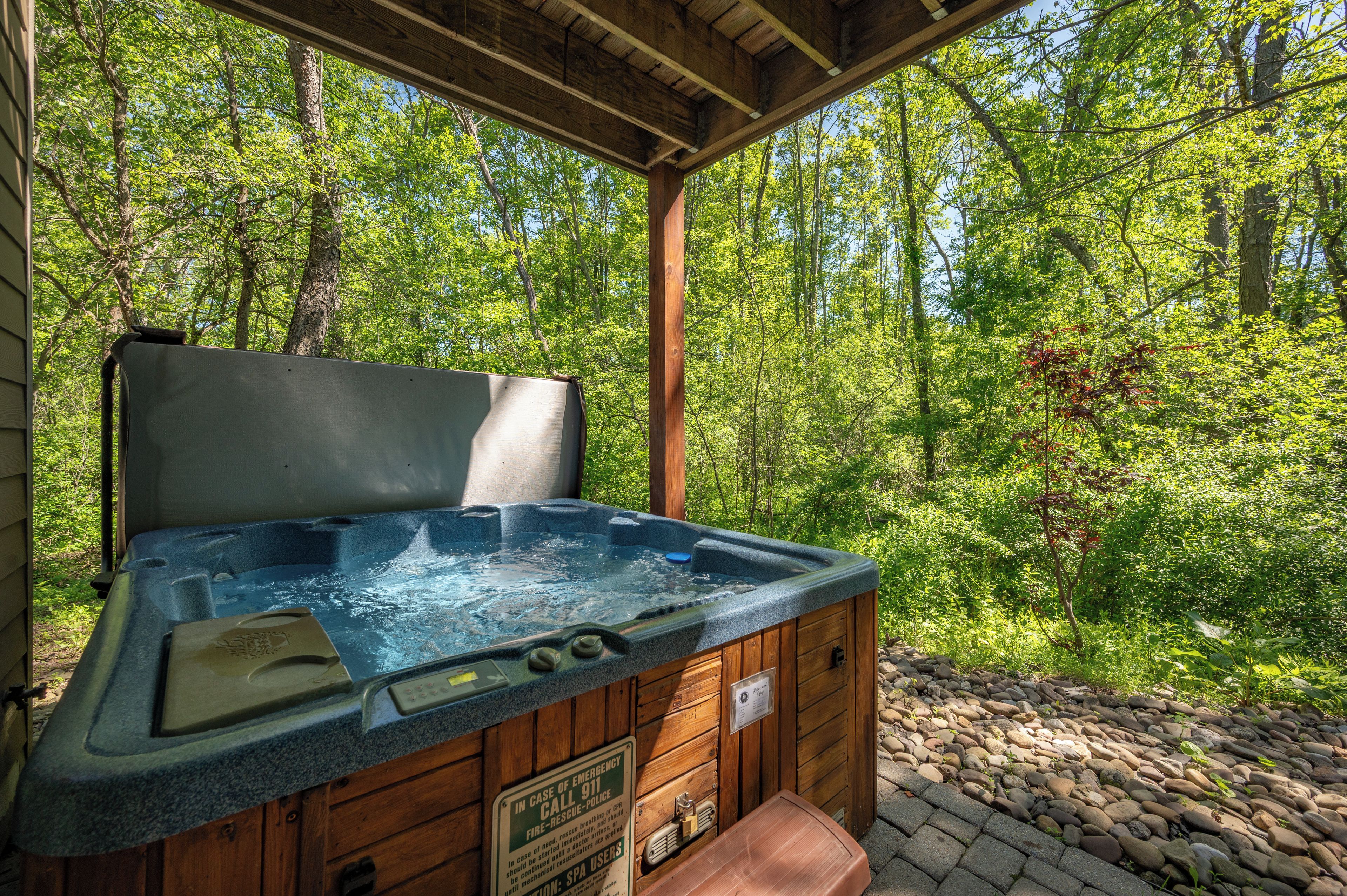 A hot tub in a wooden cabin with a view of a forest.
