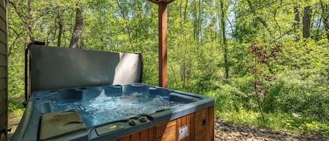 A hot tub in a wooden cabin with a view of a forest.