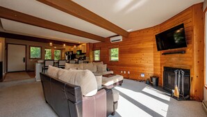 Ein gemütliches Wohnzimmer mit einer Eckcouch, einem Kamin und einem an der Wand befestigten Fernseher.