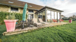 A modern house with a patio, outdoor furniture, and a glass-enclosed area. - The Vagastines (Saint-Germain-du-Plain)