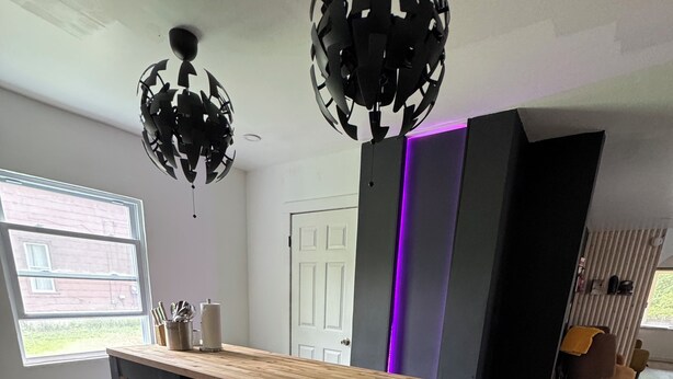A modern kitchen with a wooden countertop, black cabinets, and pendant lights. - Modern Stay By the Falls – Renovated & Walkable! (Niagara Falls)