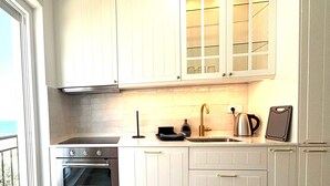 A modern kitchen with white cabinetry, a built-in oven, a sink, and a kettle. - Stella's beachfront aparthotel (Split)