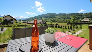 A wooden deck with a table, a bottle, and a potted plant. - Entire chalet with indoor pool jacuzzi sauna steam room (Taninges)
