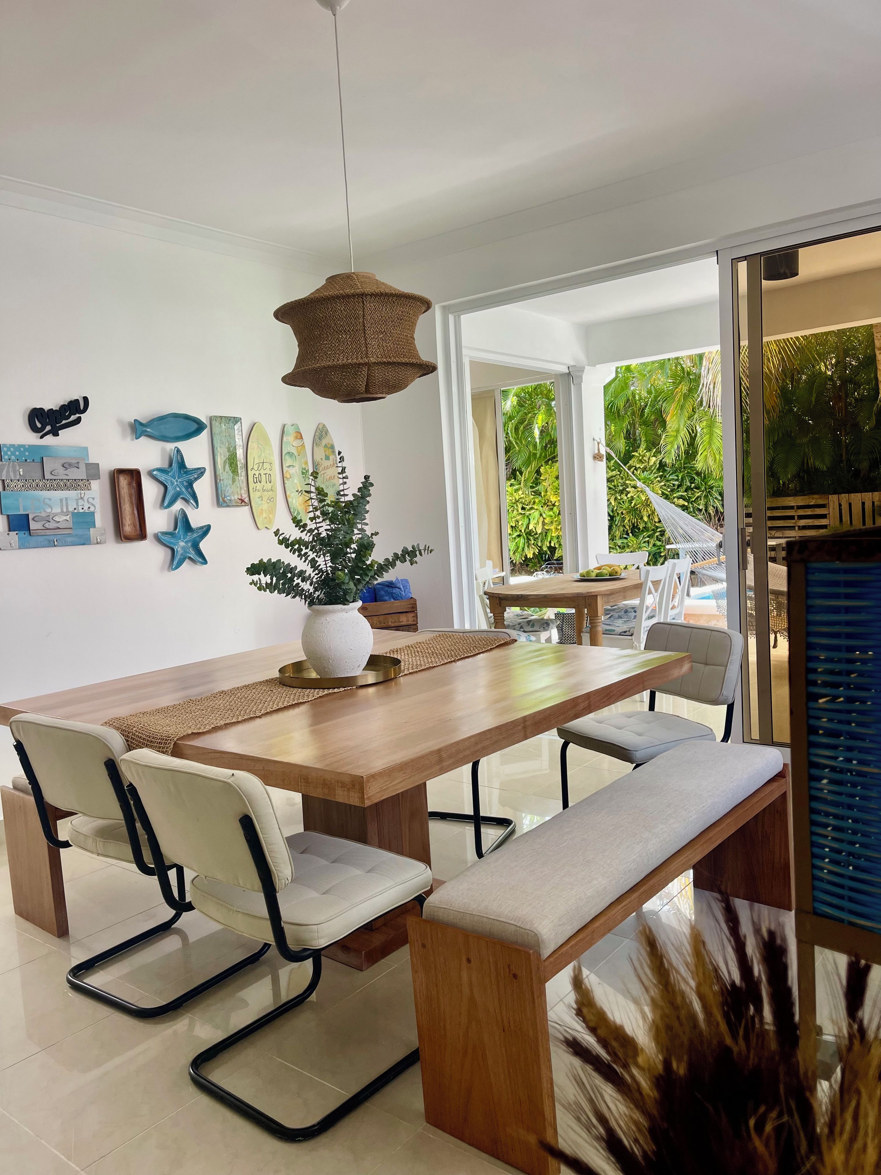 A modern dining area with a wooden table, cushioned chairs, and a hanging light fixture.