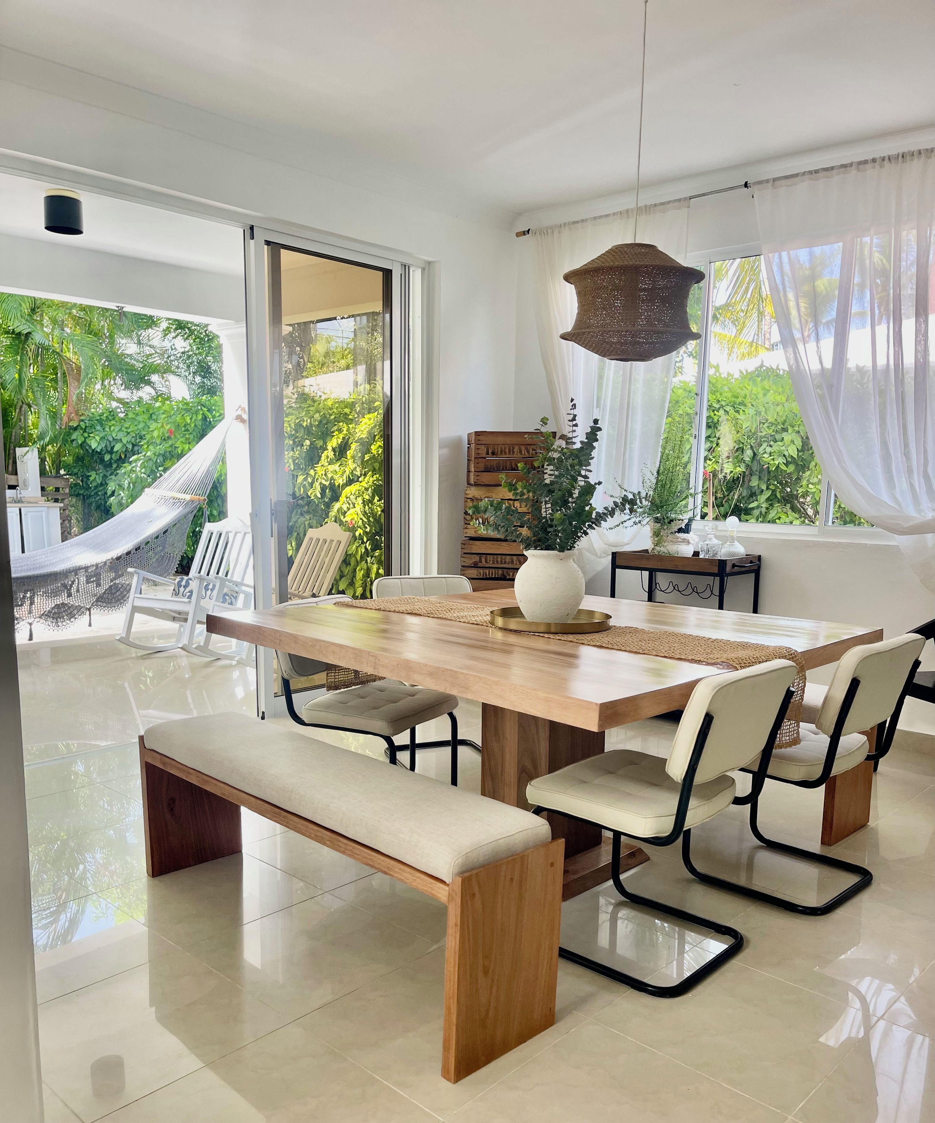 A modern dining area with a wooden table, cushioned chairs, and a bench.