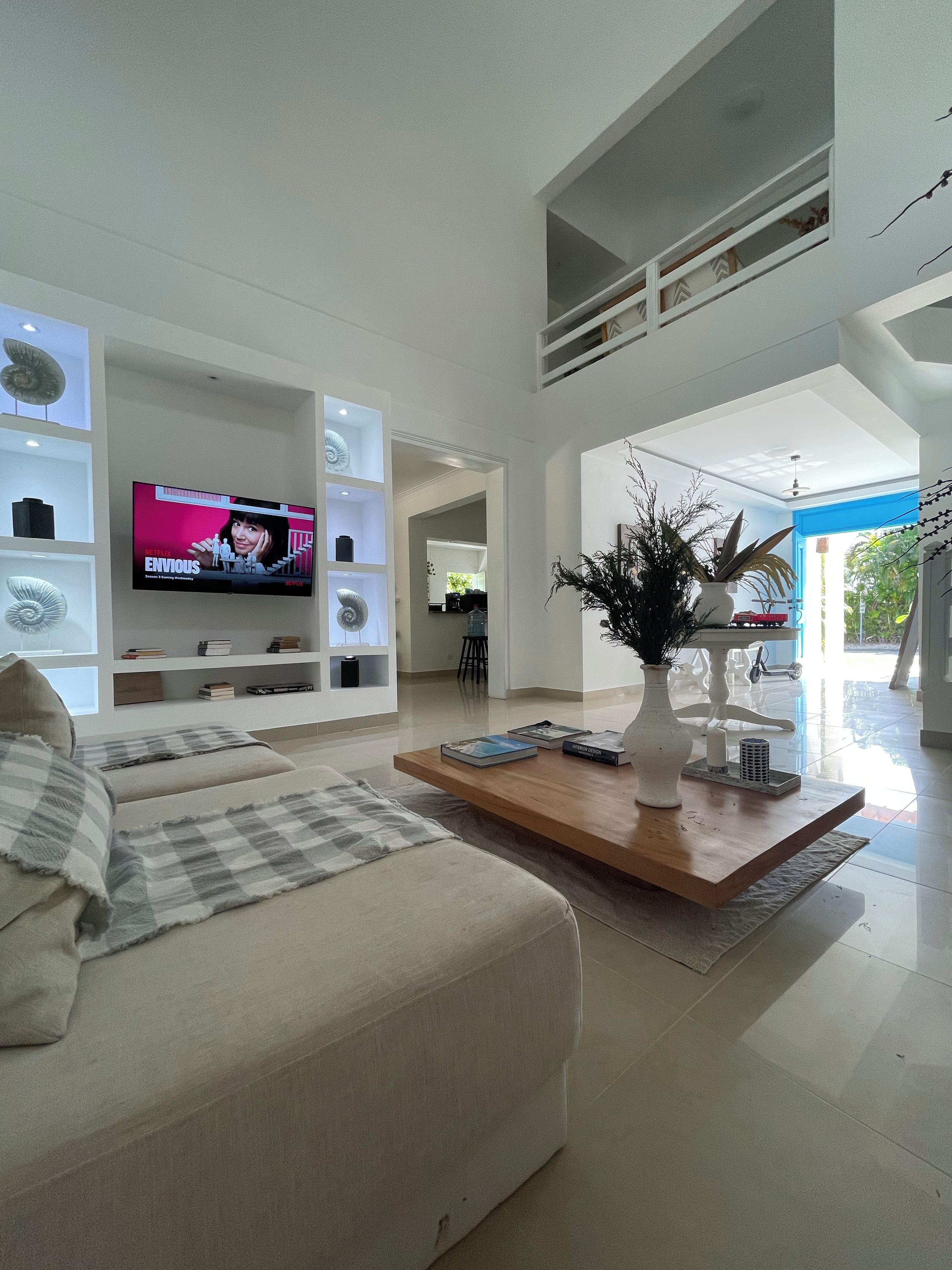 Una sala moderna con una televisión de pantalla plana, un sofá, una mesa de centro y una estantería.