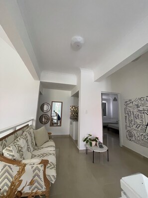 Un salon moderne avec un canapé, une petite table sur laquelle est posée une plante, et un miroir au mur.