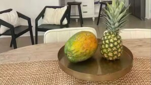 Een eetgedeelte met een ronde tafel, twee stoelen, een geweven placemat en een ananas.