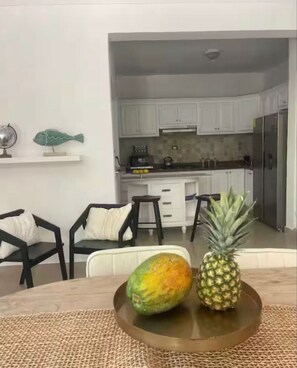 A dining area with a round table, two chairs, a woven placemat, and a pineapple.