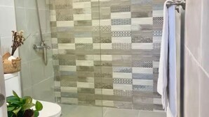 Een moderne badkamer met een douchecabine van glas, een toilet en een klein wastafelmeubel.