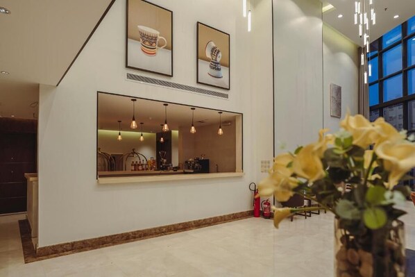 A modern interior with a reception desk, pendant lighting, and framed artwork on the wall. - W-Suites Al Souda (Abha)