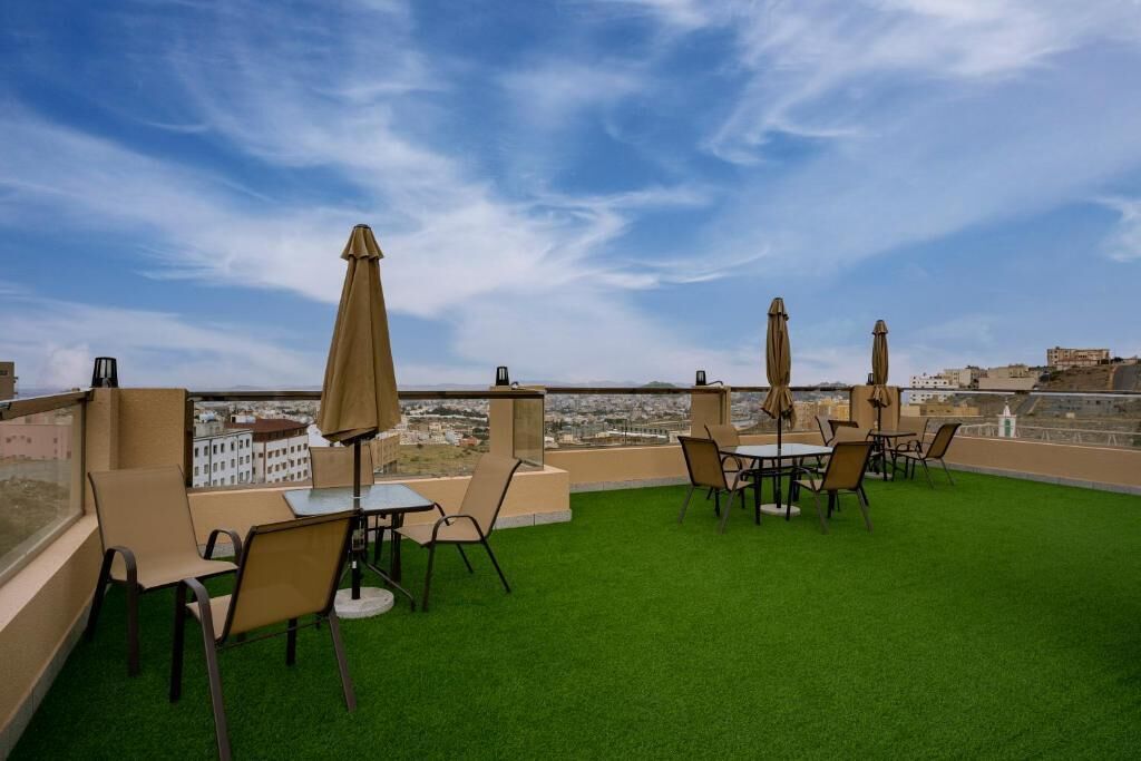 Une terrasse sur le toit, dotée d’un revêtement d’herbe artificielle, de tables, de chaises et de parasols.