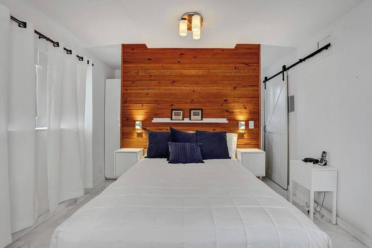 Un dormitorio con una cama grande, cabecera de madera, mesitas de noche y una mesita de noche blanca.