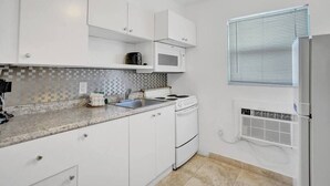 Een moderne keuken met witte kasten, een magnetron, een fornuis en een spoelbak.