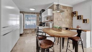 Een moderne keuken met witte kasten, een houten eettafel en barstoelen.