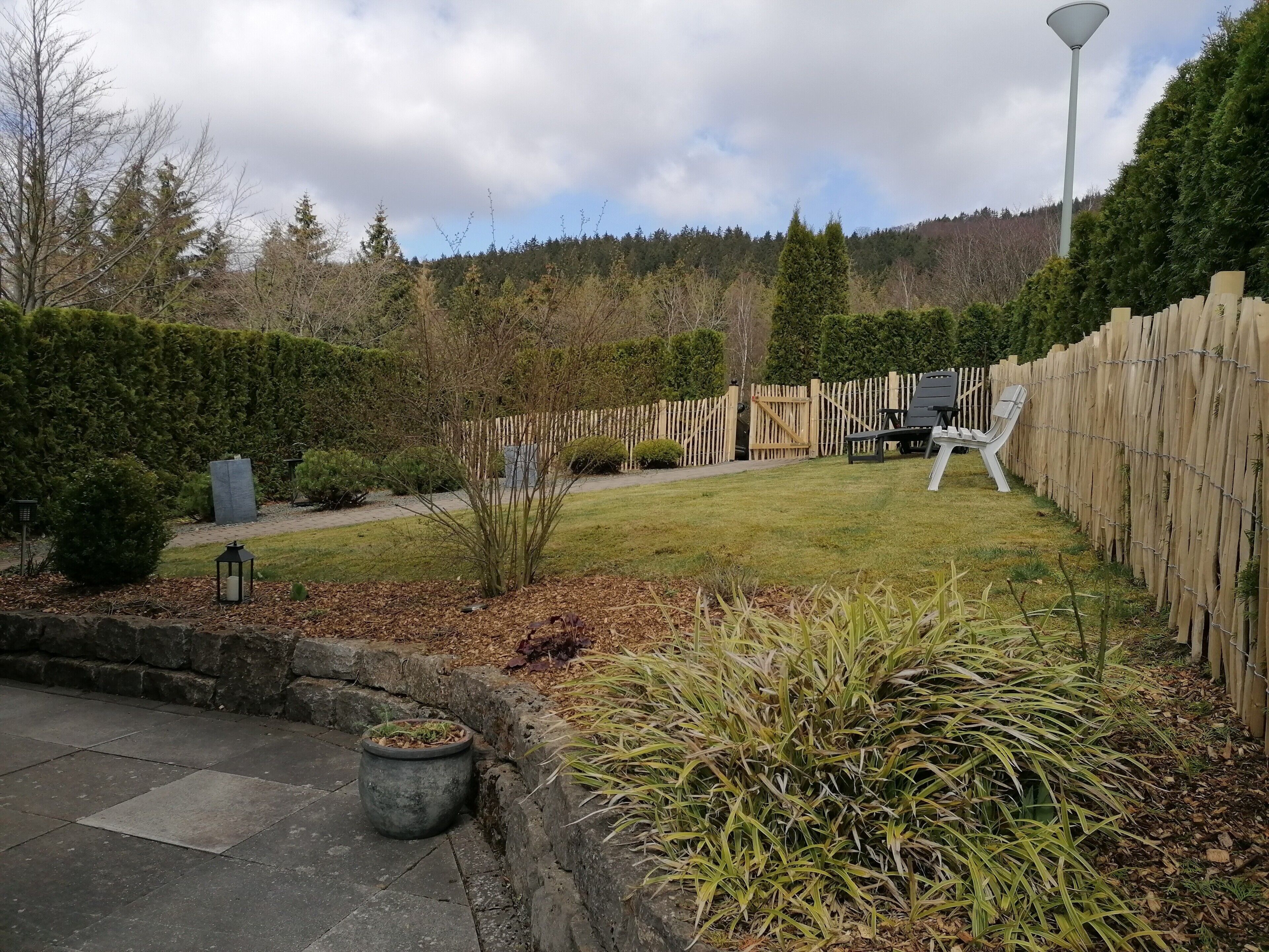 Ein Garten mit Holzzaun, Rasen und einem Kiesweg.