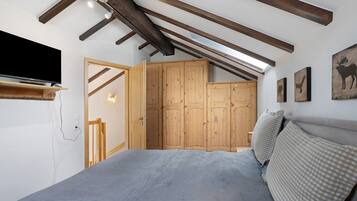 Une chambre à coucher avec un lit, une armoire en bois et un téléviseur fixé au mur.