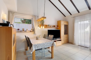 A compact living space with a dining table, chairs, a TV, and a wooden cabinet.