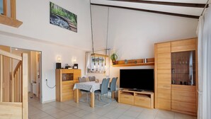 Un soggiorno moderno con zona pranzo, arredi in legno, televisore e un quadro appeso al muro.