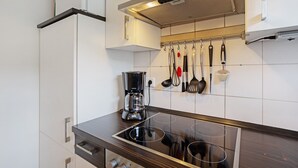 Una cucina moderna con piano cottura integrato, una macchina da caffè e vari utensili esposti a parete.