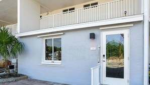 A two-story building with a white exterior, a balcony on the upper floor, and a door with a glass panel. - Lighthouse Resort and Club (Sanibel)