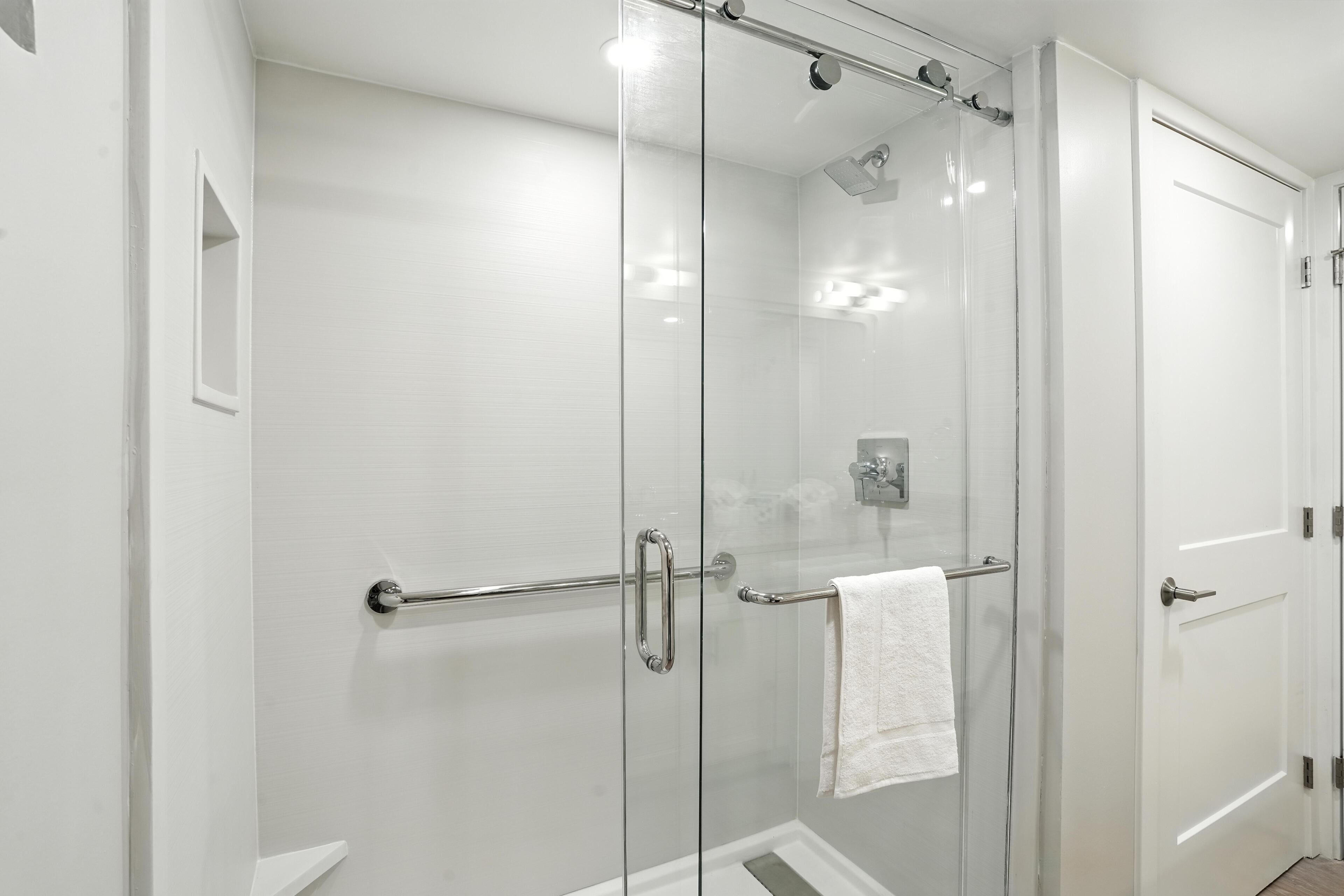 A modern bathroom with a glass-enclosed shower, a glass door, and a white towel hanging on a towel bar.